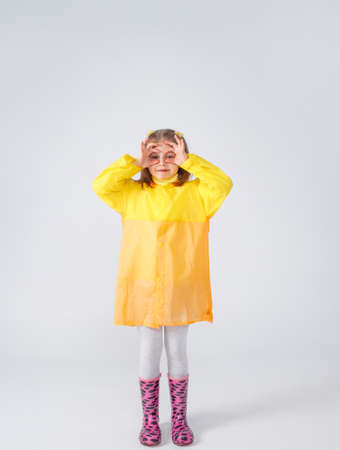 Portrait of a little girl in a yellow raincoat and boots on an isolated white background.の写真素材