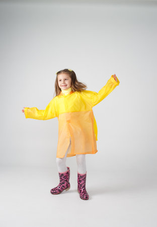 Portrait of a little girl in a yellow raincoat and boots on an isolated white background.の写真素材