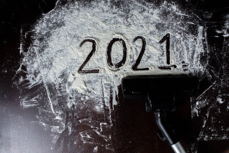Abstract background of a photo of the outgoing year 2021. Drawing from flour, the vacuum cleaner removes the figures of the outgoing year.の写真素材