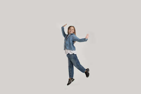 a young girl in jeans jumps with happiness on a white backgroundの写真素材