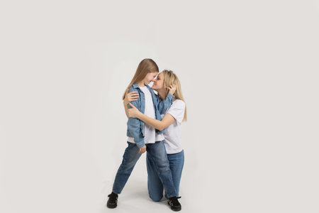 A beautiful young woman with her cute little daughter sitting on a white background.