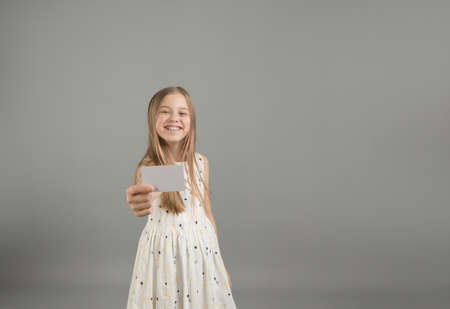 the girl holds a bank business card in her outstretched hands, place your own text on it.の写真素材