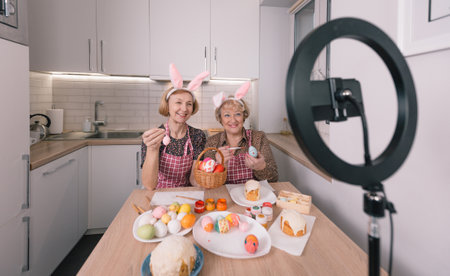 two elderly women in rabbit ears on their heads are shooting a video blog on a smartphone camera.の写真素材