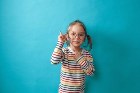 a little beautiful girl in big glasses stands on a blue background