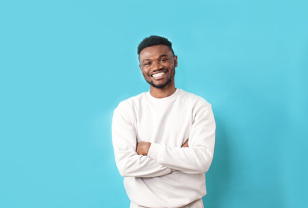 A young African-American man in a white T-shirt laughs sincerely on a blue isolated background