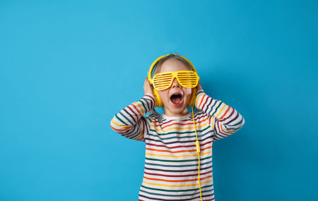 Close-up portrait of a cute charming girl listening to her favorite song in yellow headphones and...