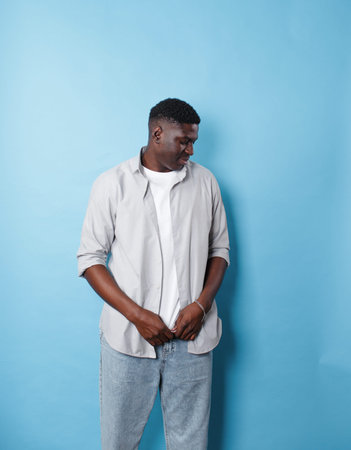 An African-American man in white clothes stands on an isolated blue background.