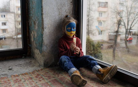 a little girl with a Ukrainian flag painted on her face prays for the Ukrainian city of Bucha, a...