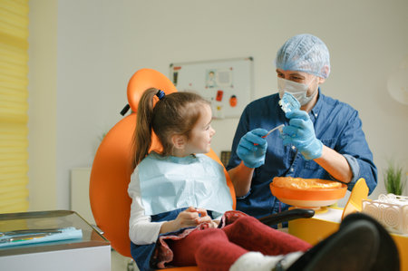a male dentist teaches a little girl how to brush her teeth properly with a toothbrush. The concept of oral care.の写真素材