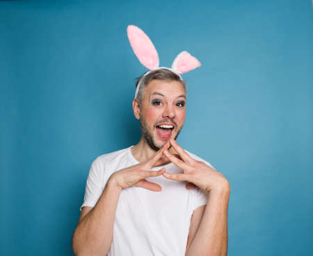 An LGBT gay man smiles on a blue background with rabbit ears on his head.の写真素材