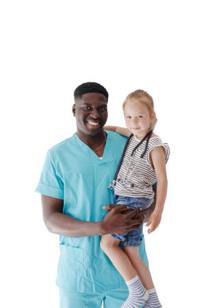 An African-American male pediatrician holds a little girl patient in his arms on a white isolated background. Children's family doctorの写真素材