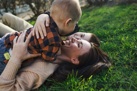 a happy mom is lying on the grass with her two young sons