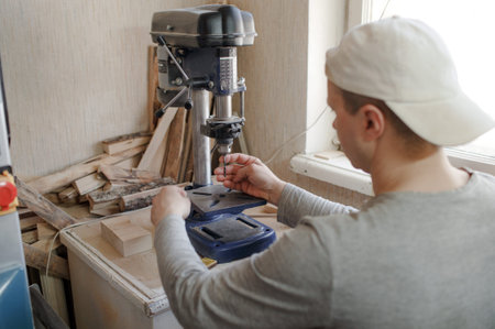 a man in the workshop inserts a drill bit into a drilling machine.