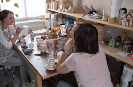 two girls shoot a video blog in an art workshop while making wooden toysの写真素材