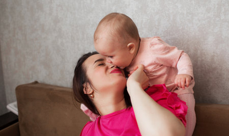 Cute little girl bites her mother's noseの写真素材