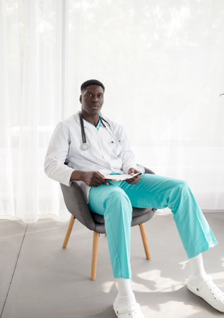 portrait of an african doctor sitting on a chair smilingの写真素材