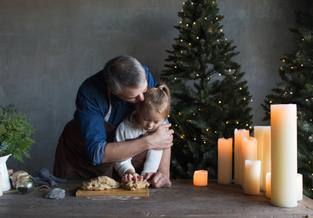 Caucasian father and daughter cook cookie dough together in the kitchen. Preparing for the celebration of Christmasの写真素材
