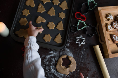 a child puts cookies on a baking sheet top view