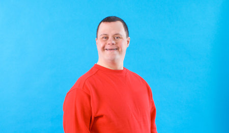a man with down syndrome on an isolated blue backgroundの写真素材