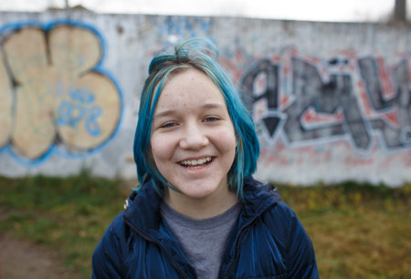teenage girl with blue colored hair on the background of street graffitiの写真素材