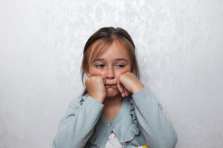 sad girl sitting on a light backgroundの写真素材