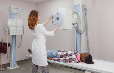 female radiologist technician, during a medical test and X-ray of a young African American woman in the laboratoryの写真素材