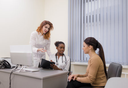 two doctors consult a young girl during an appointment at a modern clinicの写真素材