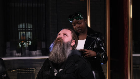 African-American hairdresser girl prepares a man for a haircut in a barbershopの写真素材