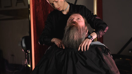 a girl in a barbershop throws a black cloth on a client before starting a haircut.の写真素材