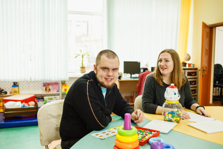 an autistic adult is undergoing rehabilitation with an assistant in the classroom.の写真素材