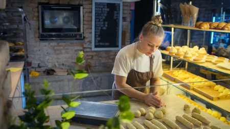 A view of a professional woman baking on a white kitchen table in the open kitchen of a bakery in a cafe. The process of making homemade cakes.の写真素材