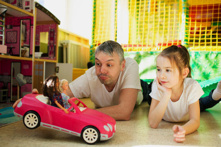 a happy dad with a little daughter frolics in a children's play center.の写真素材