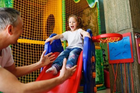 a happy girl with her father rides a roller coaster at the children's play center.の写真素材