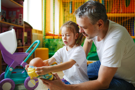 a happy girl with her father plays with dolls in a children's play center.の写真素材