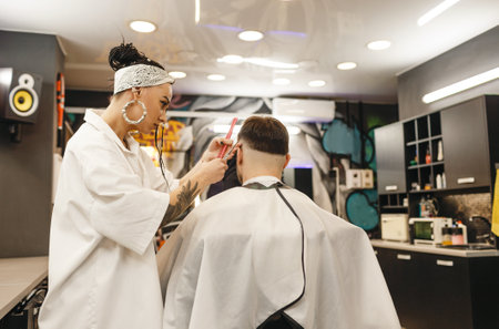 A hairdresser girl cuts a man's hair in a barber shop. Professional men's hair salon. Barbershopの写真素材