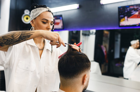 A hairdresser girl cuts a man's hair in a barber shop. Professional men's hair salon. Barbershopの写真素材