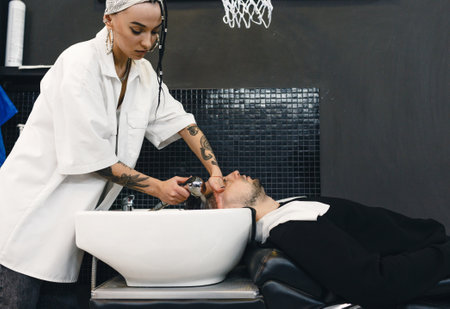 A barber washes a man's head in a barber shop. Men's professional hair salon. Barbershop.の写真素材