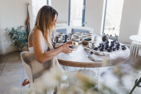 A young woman sculpts from clay in her pottery workshop. Pottery work. Creation of clay productsの写真素材