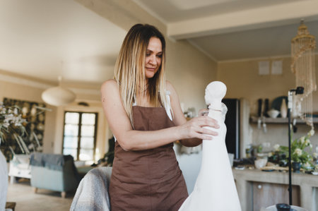 a woman is working on a statue in her pottery workshop. Pottery work. Creation of clay products.の写真素材