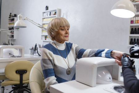 An elderly woman does a professional manicure in a beauty salon.の写真素材
