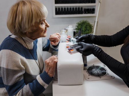 An elderly woman does a professional manicure in a beauty salon, chooses the color of nail polish to cover her nails.の写真素材