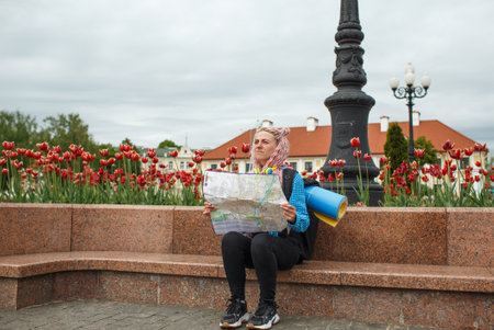 An attractive young tourist explores a new city. A girl with long pink hair holds a paper map of the city scheme in her hands. I'm traveling in Europeの写真素材