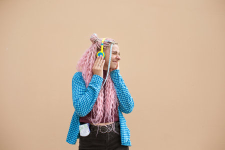 Portrait of a young woman with pink long hair and a blue shirt. A girl with headphones on a bright background. Empty space for advertising text.の写真素材