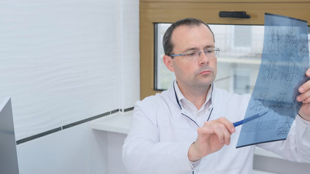 Doctor looking at an x-ray image of a patient in his officeの写真素材