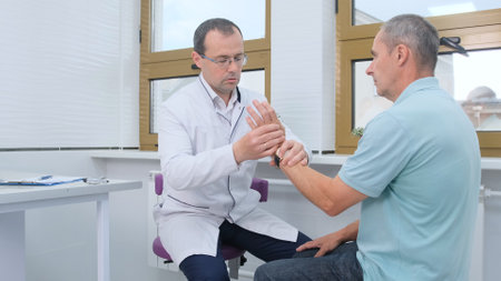 Senior male physiotherapist helping senior patient with pain in wrist.の写真素材