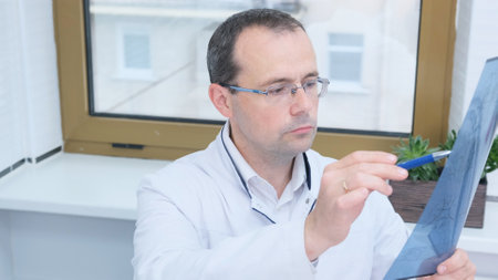 Doctor looking at an x-ray image of a patient in his officeの写真素材