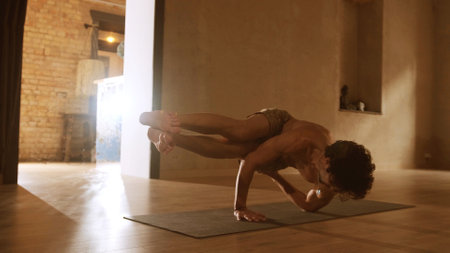 A young and athletic man does yoga and performs complex asanasの写真素材