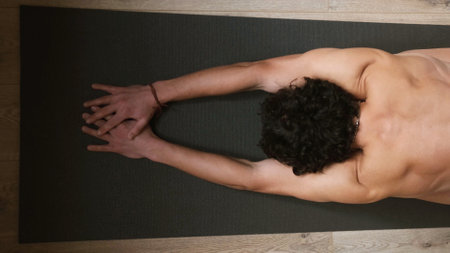 Top view of a young man with a bare torso at a warm-up before a yoga workout.の写真素材