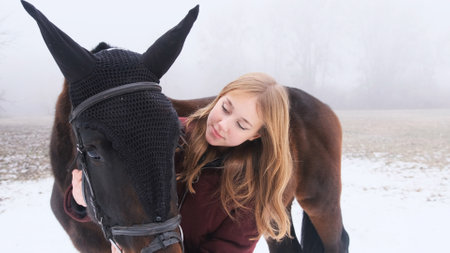 A young beautiful girl hugs a horse in nature in the fog.の写真素材