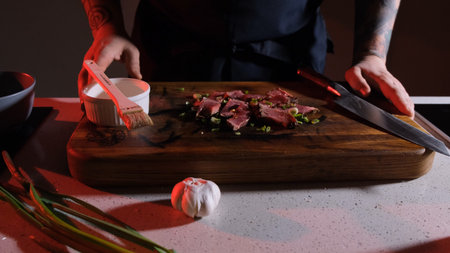 pieces of cooked and sliced meat sprinkled with fresh onions lie on a wooden board in front of the...